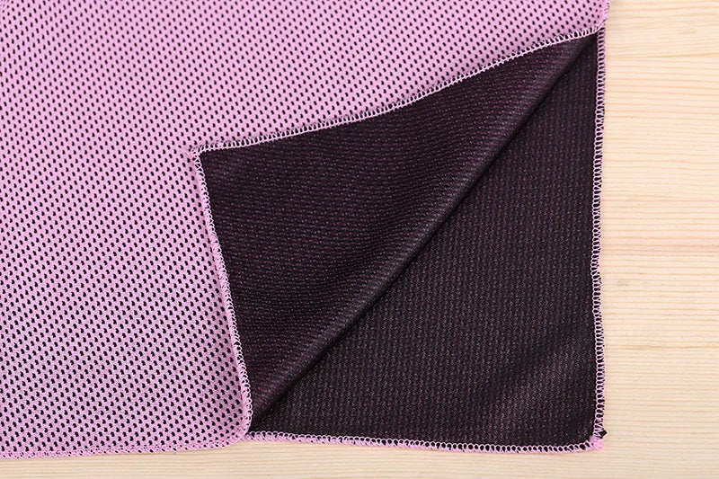 A close-up of a purple microfiber cooling towel folded next to a black one on a wooden surface.