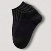 Una pila de calcetines de algodón unisex negros y transpirables, vistos desde arriba.