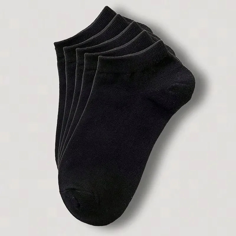 Una pila de calcetines de algodón unisex negros y transpirables, vistos desde arriba.