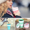 Reusable silicone collapsible coffee cups with lids in various colors and a metal coffee grinder.