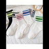 A collection of white socks featuring various striped patterns in black, pink, blue, and green.