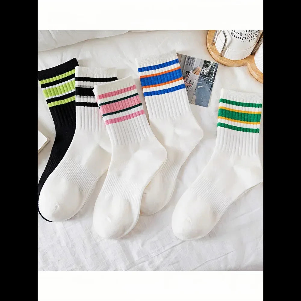 A collection of white socks featuring various striped patterns in black, pink, blue, and green.