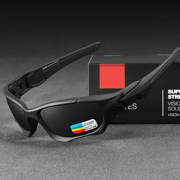 A pair of black polarized sports sunglasses resting on a dark surface next to a black box.