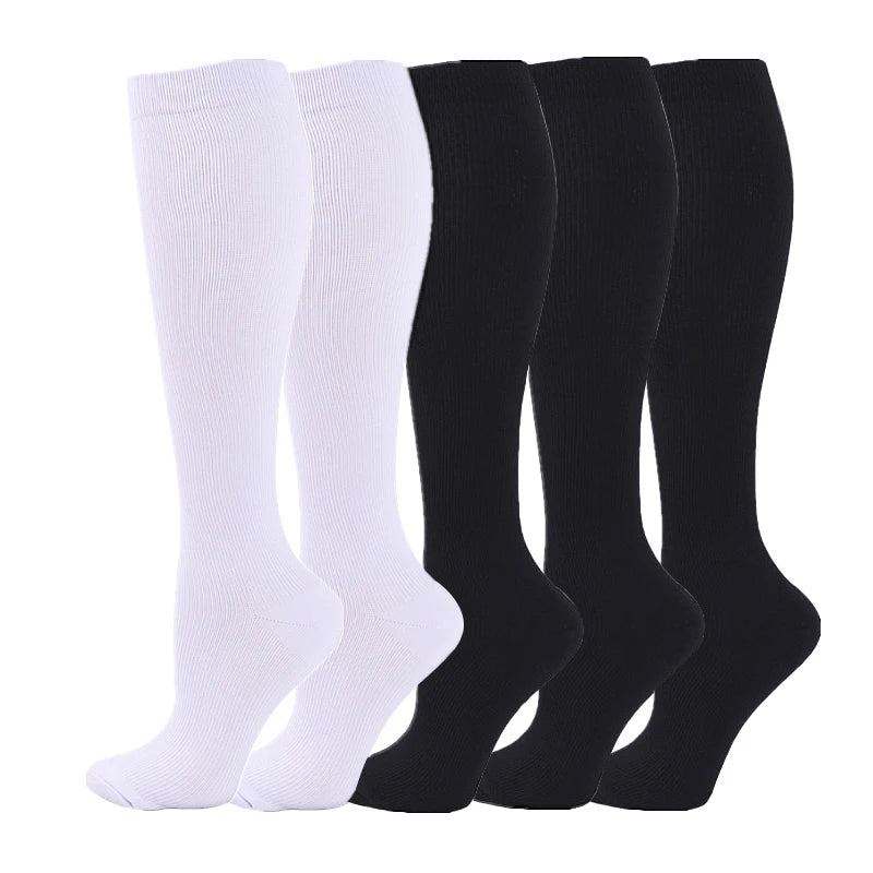 A set of four black and white medical grade compression socks for veins and sports.