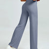 A woman is modeling high waisted gray yoga pants while standing.