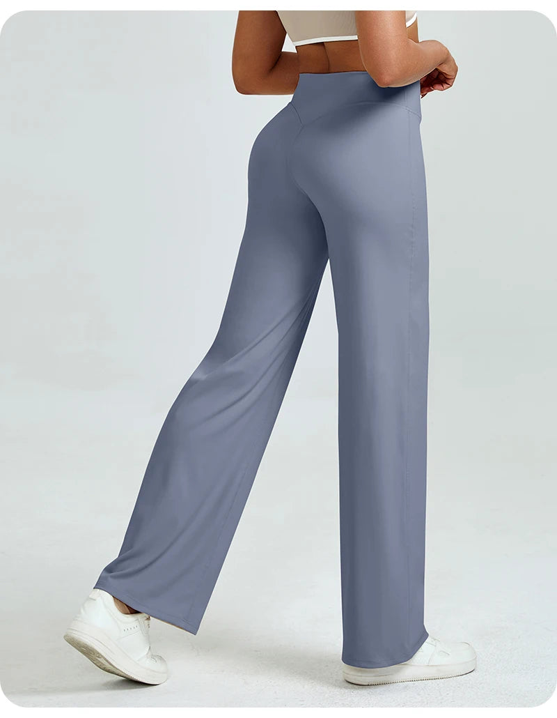 A woman is modeling high waisted gray yoga pants while standing.