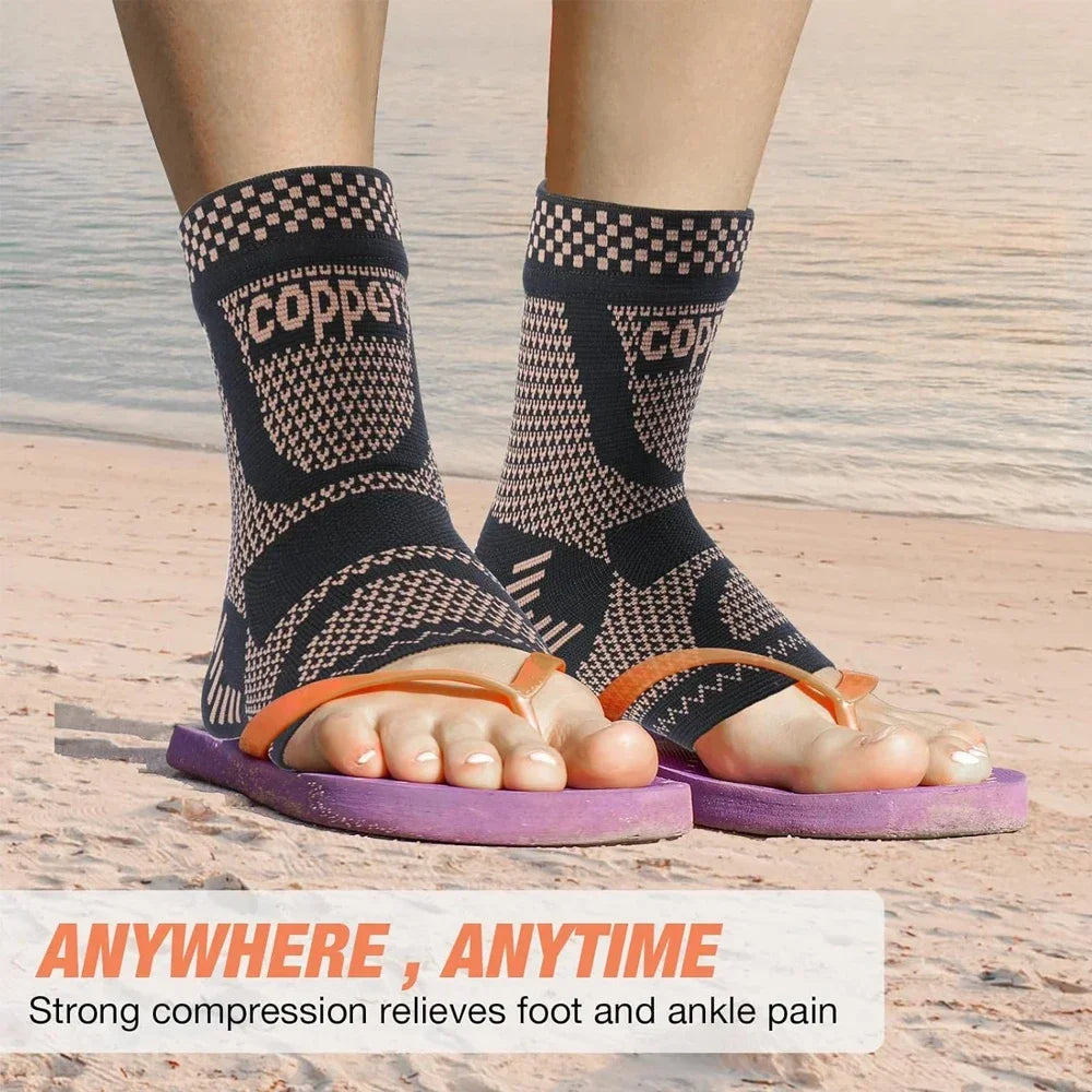 A person wearing black copper infused ankle compression socks on a sandy beach.