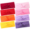 A collection of nine knotted elastic sports headbands in various shades including maroon, red, pink, orange, and purple.