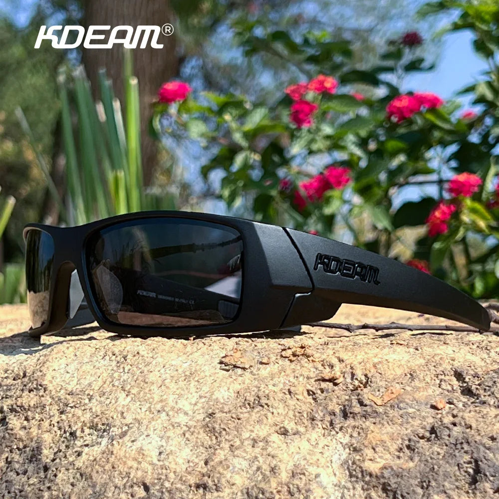 Black KDEAM polarized sports sunglasses resting on a rough, light-colored rock outdoors.