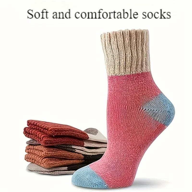 A close-up of a pink and blue knit crew sock with a ribbed cuff, displayed next to a stack of similar socks.