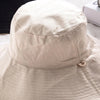 A beige double-sided wide brim bucket hat is shown from the front, highlighting its textured fabric and brim.