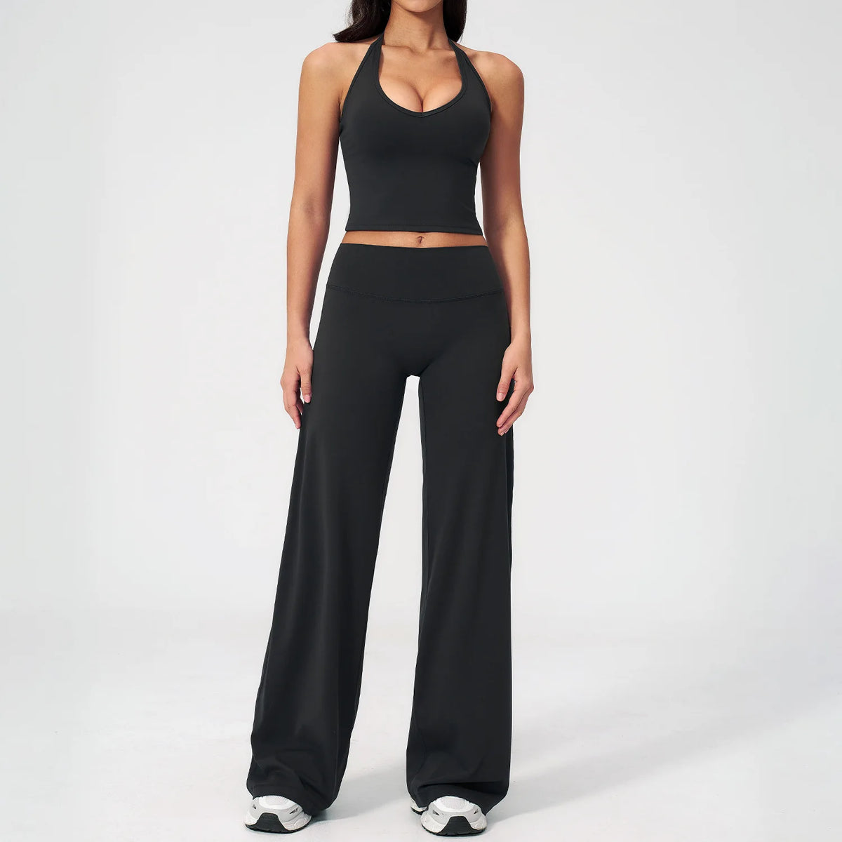 A woman wearing a black women's premium fitness tracksuit top and matching pants.