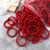 A pile of red elastic hair bands in a clear plastic bag on a gray surface.
