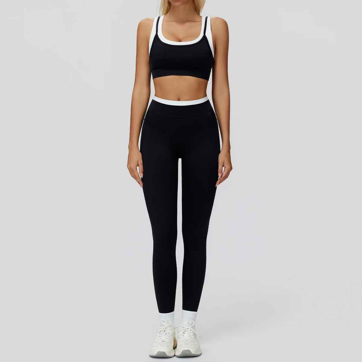 Eine Frau trägt ein schwarz-weißes Yoga- und Gym-Trainingsanzug-Set mit Crop-Top und passenden Leggings.