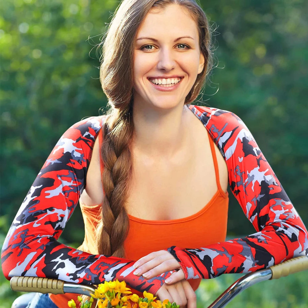 A smiling woman wearing orange athletic wear and red camouflage arm sleeves outdoors.