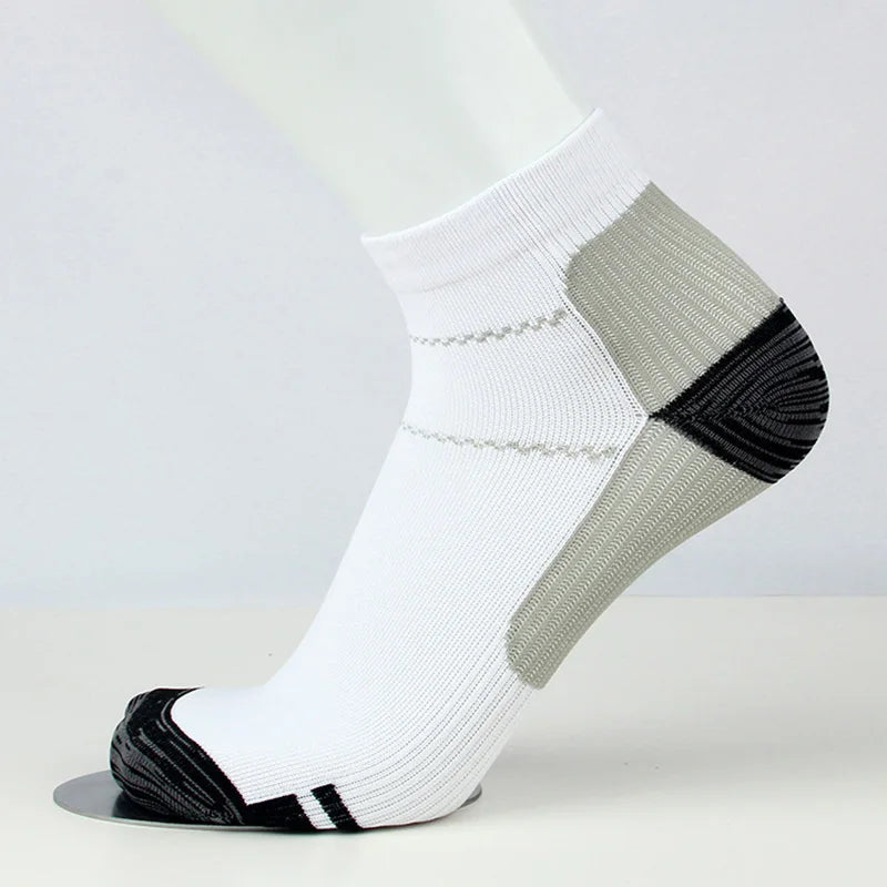 Chaussettes de compression blanches avec des rayures grises et noires sur une jambe blanche.