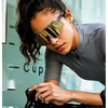 A woman wearing polarized performance sunglasses is shown leaning over a bicycle handlebar.