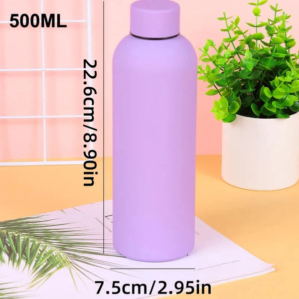 A purple 500ml insulated stainless steel thermos cup standing next to a white potted plant.