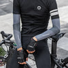 Una persona vistiendo ropa deportiva negra y mangas está sentada en una bicicleta.
