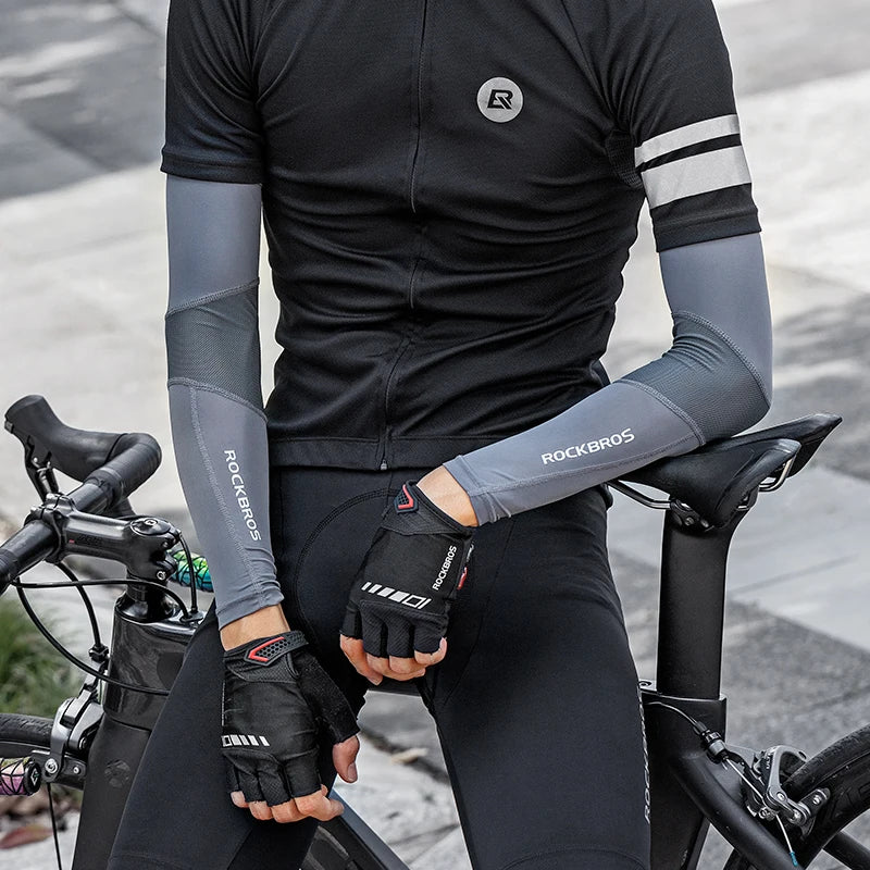 Una persona vistiendo ropa deportiva negra y mangas está sentada en una bicicleta.