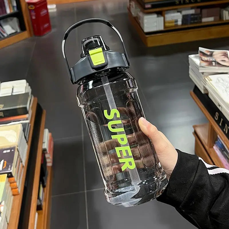 A hand holds a clear insulated sports water bottle with a yellow lid and straw against a gray background.