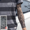 A person is wearing a gray t-shirt featuring text and a black geometric tattoo sleeve on their arm.
