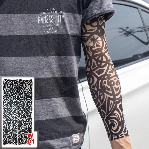 A person is wearing a gray t-shirt featuring text and a black geometric tattoo sleeve on their arm.