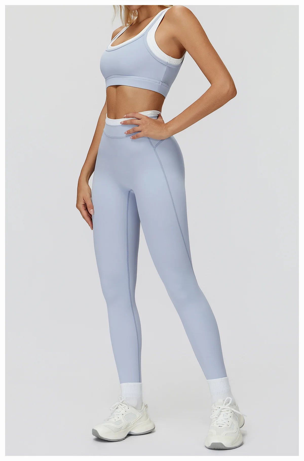 Eine Frau trägt ein hellblaues zwei-teiliges Yoga- und Gym-Trainingsanzugset mit Crop-Top und Leggings.