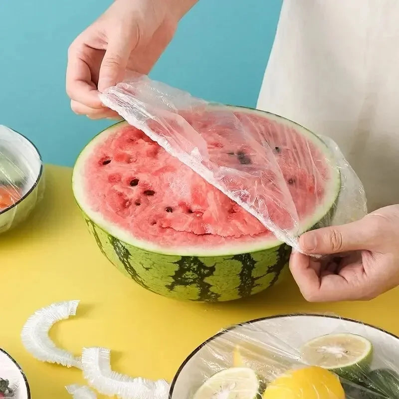 Una mano coloca una gorra de ducha desechable transparente sobre una rebanada de sandía.