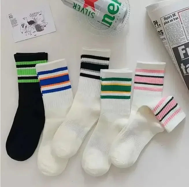 A collection of striped casual socks in black, white, and various colors are displayed on a white surface.