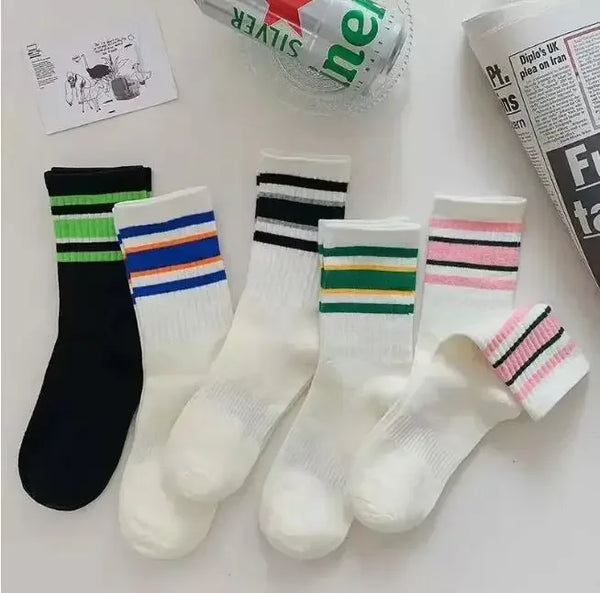 A collection of striped casual socks in black, white, and various colors are displayed on a white surface.
