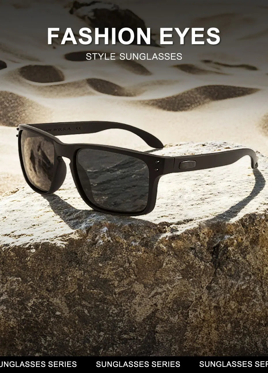 A pair of dark-framed sunglasses resting on a rough, light-colored rock against a sandy background.
