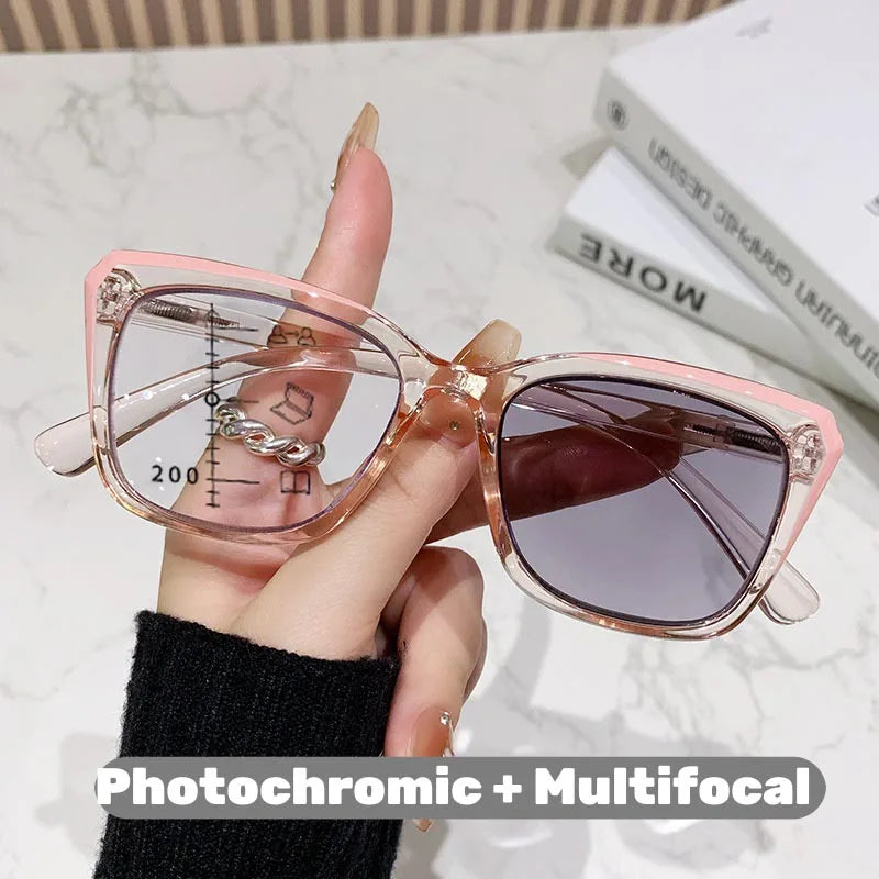 Eine Hand hält eine rosa photochromische multifokale Brille mit einer Elfenbein- oder Schildpattelschale.