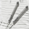 A close-up of two gray adjustable ropeless battle ropes casting shadows on a light background.