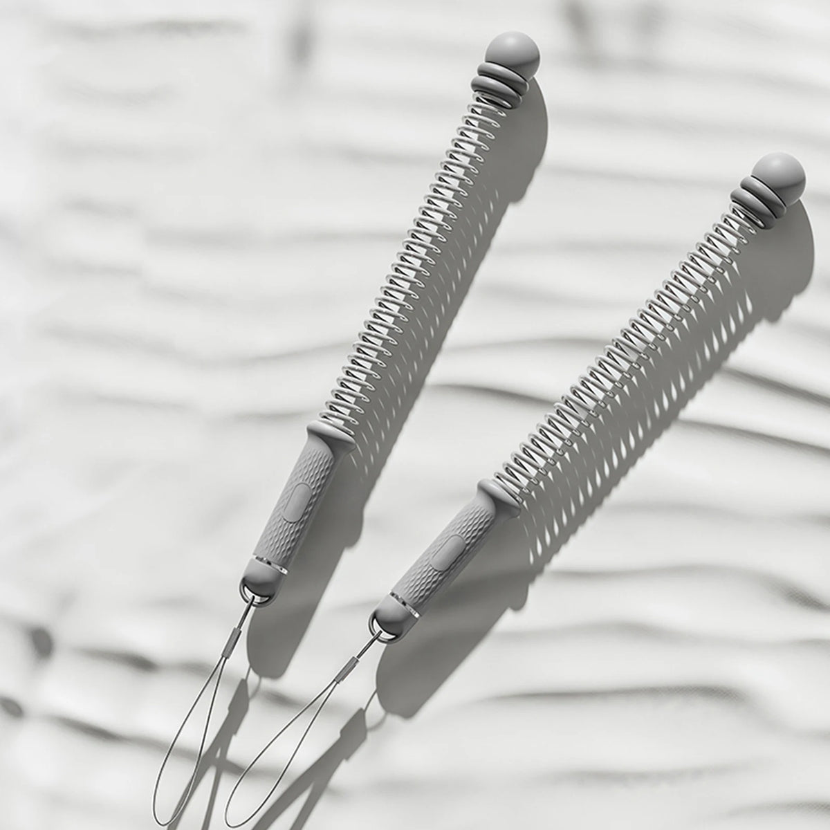 A close-up of two gray adjustable ropeless battle ropes casting shadows on a light background.