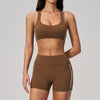 A woman models a brown two-piece yoga and sports tracksuit set consisting of a cropped top and matching shorts.
