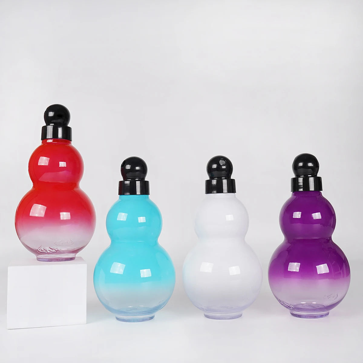Eine Sammlung von kürbisförmigen Sportflaschen aus rotem, blauem, weißem und violettem Glas.
