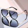 Classic gradient aviator sunglasses with black frames and gold accents displayed on a light surface.
