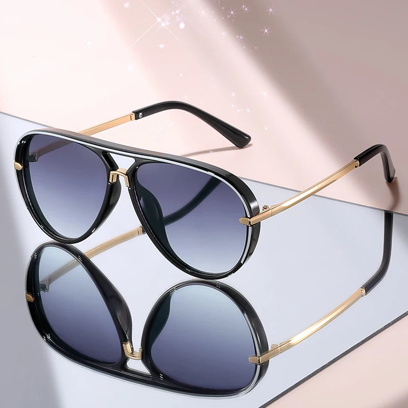Classic gradient aviator sunglasses with black frames and gold accents displayed on a light surface.