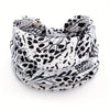 A close-up of a black and white leopard print fabric used as a stylish scarf or headband.