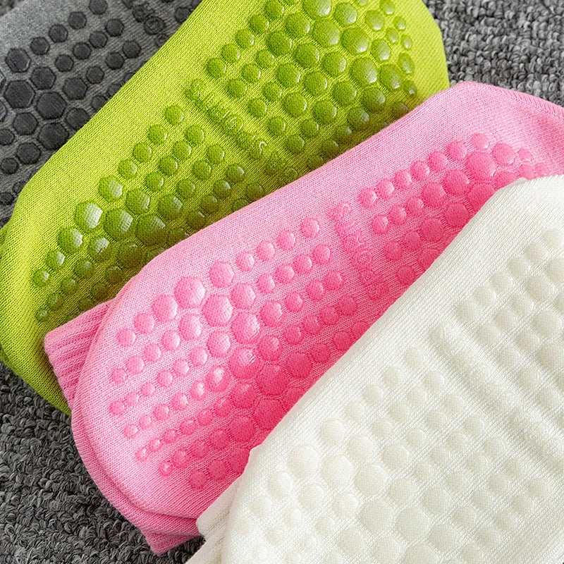 Nahaufnahme von drei Paar atmungsaktiver rutschfester Yoga- und Fitnesssocken in Limettengrün, Pink und Weiß.