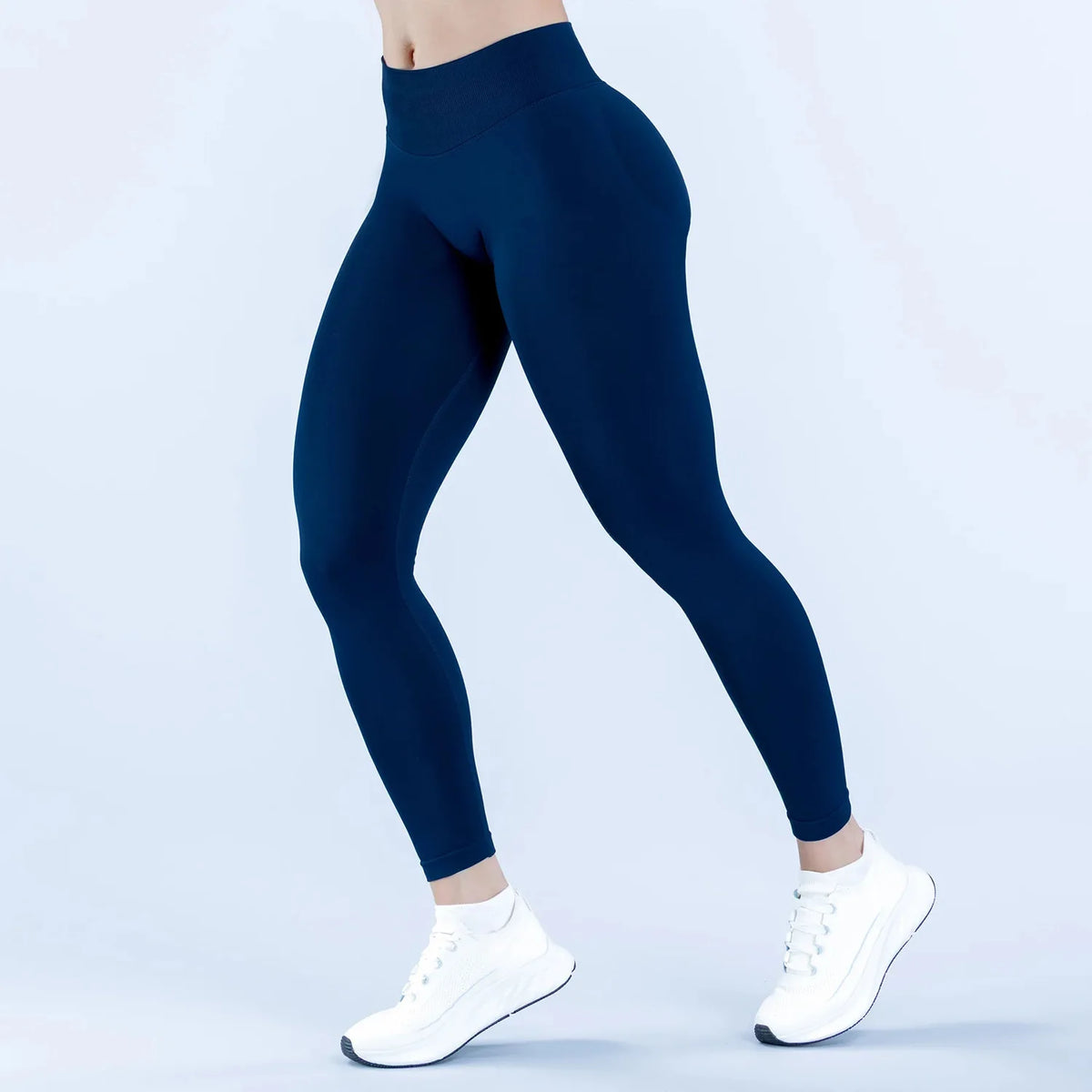 A person is modeling dark navy high-waisted seamless yoga leggings in a studio setting.