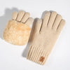 A pair of beige knit gloves with a fluffy suede cuff and a brown leather tag.