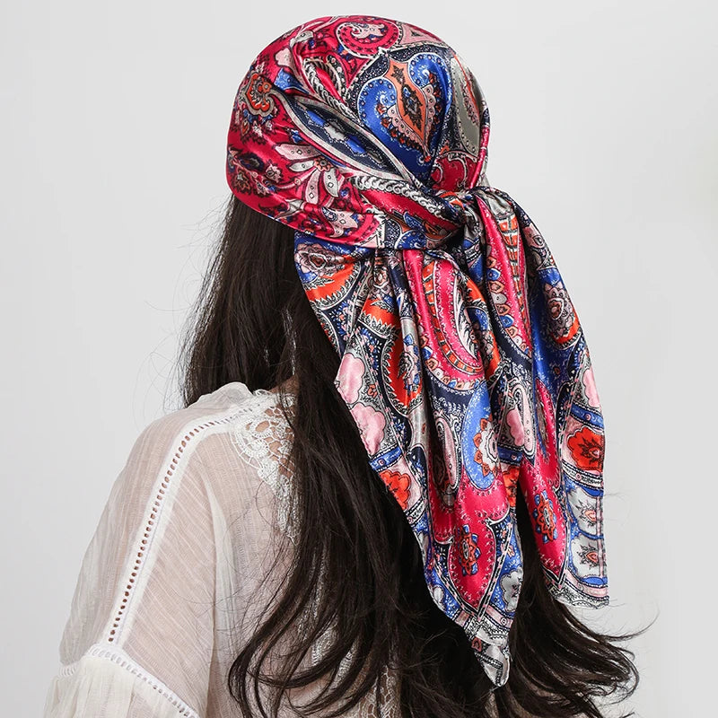 A woman wearing a vibrant red and blue paisley silk shawl scarf draped around her neck.