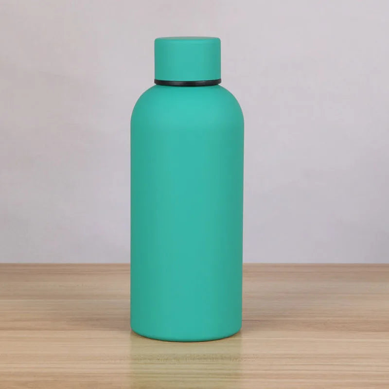 A teal double-layer vacuum thermos cup standing on a wooden surface.