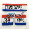 مجموعة من ثلاث أساور تحمل نصوص 'NEVER GIVE UP'، و 'U ME'، و 'HLR' باللونين الأسود والأبيض على خلفية حمراء وزرقاء.