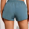 A close-up view of a teal athletic pair of shorts with mesh pockets worn by a model.