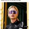 A woman wearing purple polarized sunglasses and a black athletic shirt is shown outdoors.