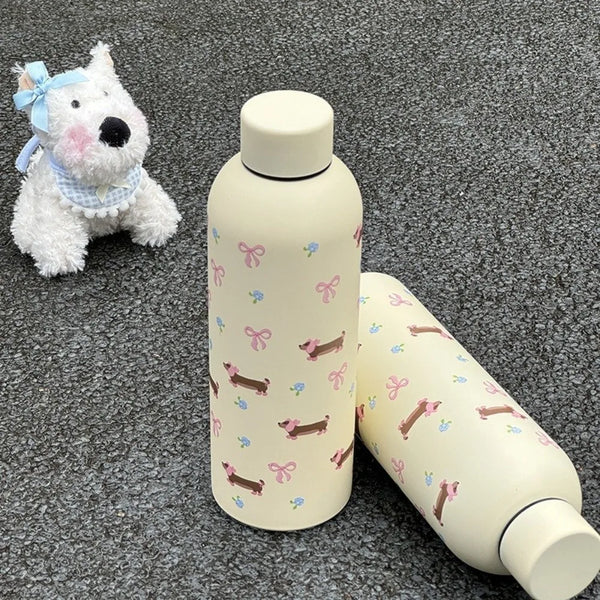A light beige double-walled insulated stainless steel travel mug next to a small white dog toy.