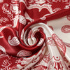A close-up of a red and white patterned satin fabric draped in elegant folds.